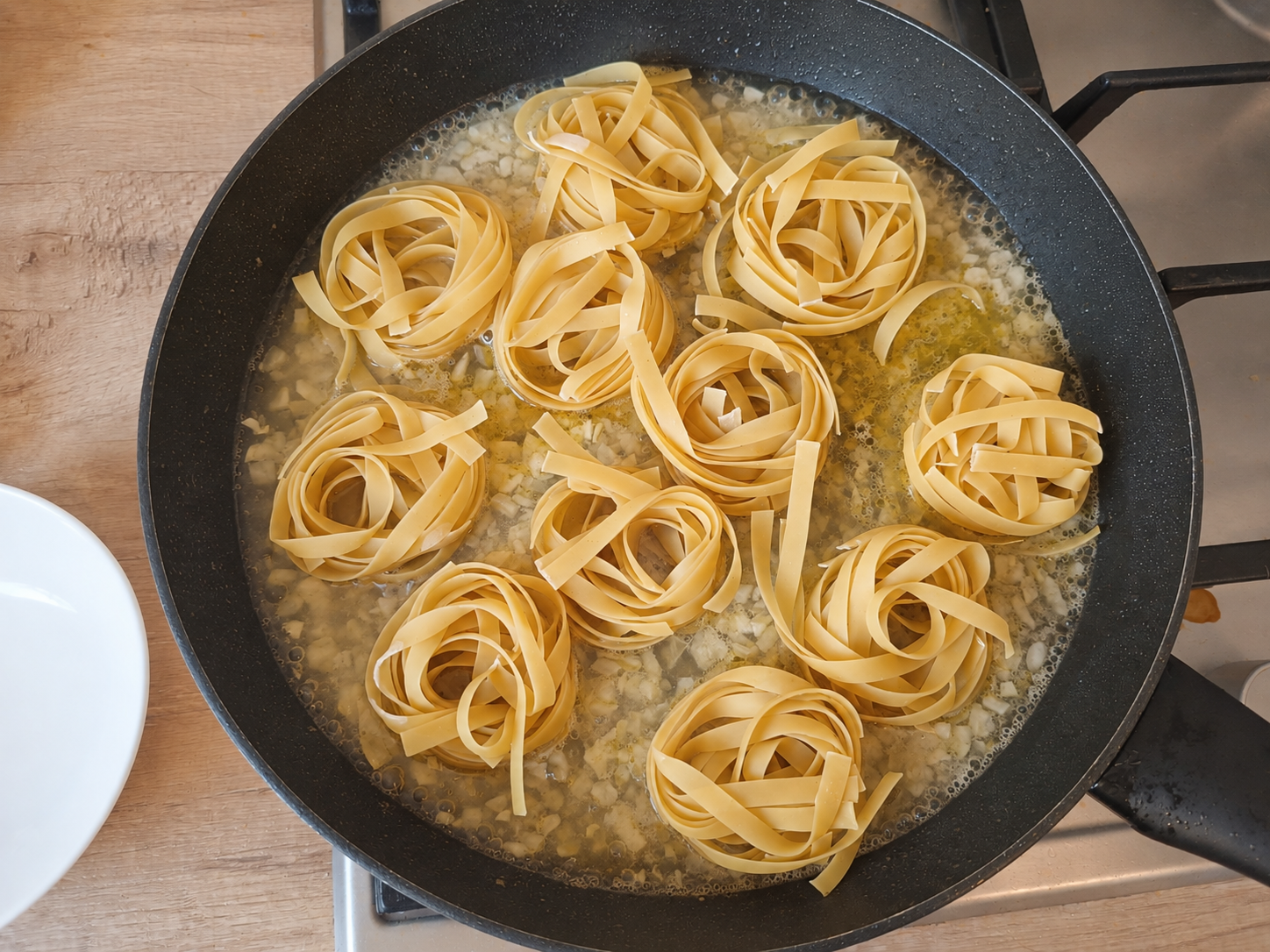Gniazdka tagliatelle gotowane w bulionie na patelni